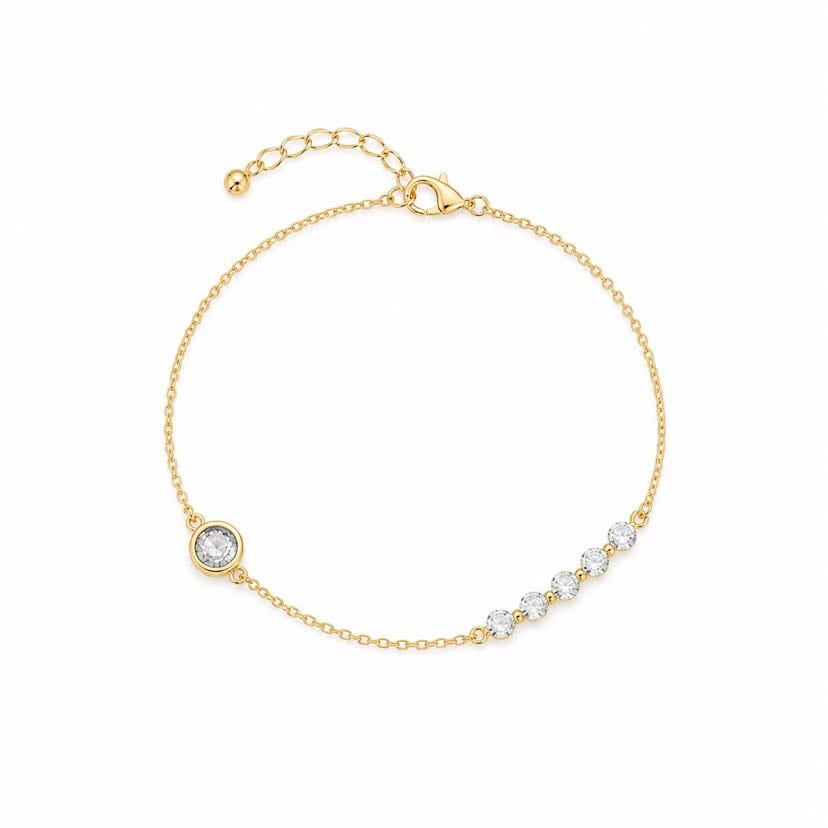 Bracelet Cascata à plat sur fond blanc, chaîne or en cercle, cabochon serti bezel d'un côté et 5 cristaux en cascade gradient de l'autre, fermoir mousqueton avec bille pendante en haut
