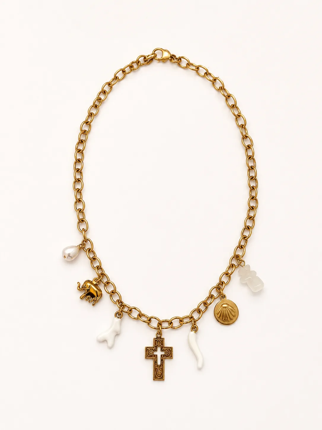 Collier Cétina à plat sur fond blanc, chaîne forçat d'or et 6 pendentifs visibles — éléphant d'or, corail blanc, perle baroque, crucifix byzantin ciselé, coquille pèlerine et corail blanc