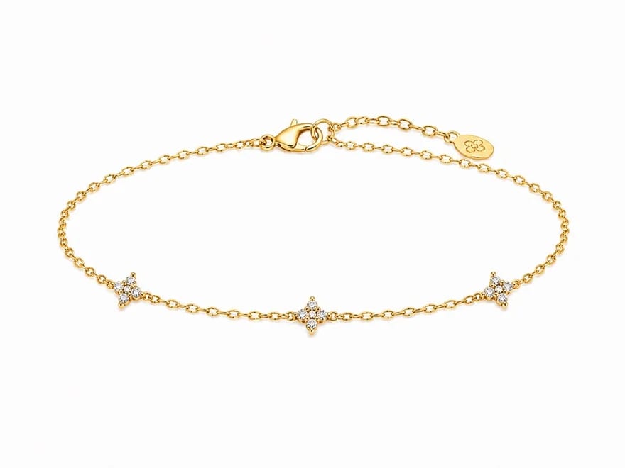 Packshot bracelet Lueur à plat sur fond blanc d'atelier, chaîne forçat or rose étirée en arc, trois petits motifs étoilés pavés de zircons équidistants, fermoir mousqueton et plaque signature fleur SOLINA à droite